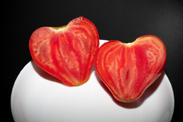 Heart shaped tomato isolated on white plate.
Round pink red tomato with a nose that forms a heart...