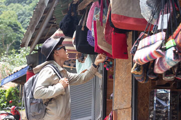 Male tourist wearing hat walking through open air market exploring village, shopping, sightseeing, community, tradition, goods, discovery, photography, transportation, travel scene