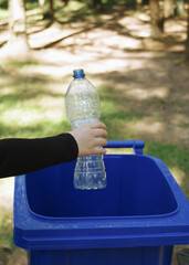 children clean up the forest by throwing empty bottles into a bag and a trash can