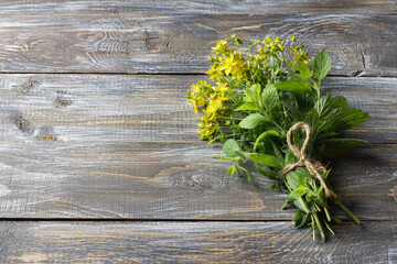 Bundle of fresh St. John's wort and mint tied with twine on rustic wooden table. Organic medicinal herbs used for natural healing, herbal remedies and and herbal tea