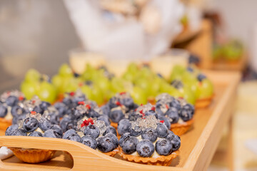 A colorful and delicious buffet spread featuring a wide variety of international dishes, including fizzy cola, lemon tart, creamy cheesecake, blueberry tart, crispy fried chicken, and savory pasta
