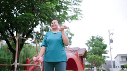 Strong and active senior Asian woman doing strength training with pink dumbbells in the park, showcasing a healthy, fit, and empowered retirement lifestyle.