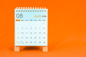 August 2026 desk calendar stand on orange color textile background.