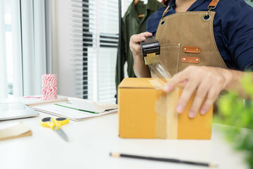 A man is packing things into boxes. He uses scotch tape and string to tie the boxes, writes...