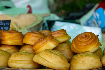 A close-up view of traditional smoked cheese rolls stacked on a market stall. 
