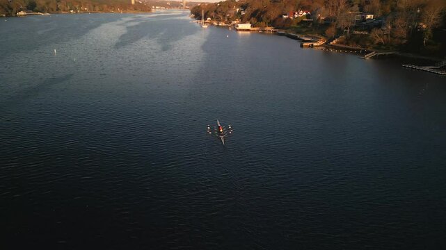 Drone View Displays A Rowing Crew Cutting Through Glassy Water At Sunrise In Halifax, Nova Scotia, Canada, Framed By The Warm Glow Of Early Light On The East Coast.