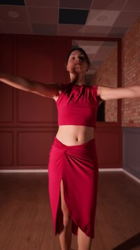 A beautiful woman in a red dress and high heels performs a sensual Latin dance. Her passionate salsa or bachata moves are full of rhythm and grace, perfect for a dance class or show.