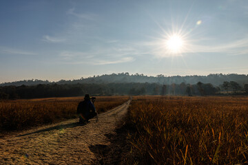 photographer is crouching to capture a sunrise or sunset in the nature.