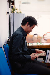 Thoughtful man holding book in room with blue chair and soft lighting, serene moment