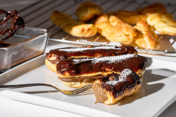 Delicious Chocolate Eclairs with Cocoa Icing on a white plate on a table