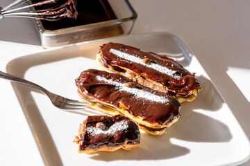 Delicious Chocolate Eclairs with Cocoa Icing on white plate