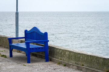 Lonely blue bench on a concrete pier under a cloudy sky in Nida Lithuania