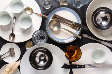 Top view of an empty plates, bowls, glasses and cutlery placed on a black chalkboard background. Flat lay. Top view. Food concept.