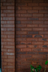 Rustic brickwork facade featuring a textured wall and pillar architectural elements with lush flora