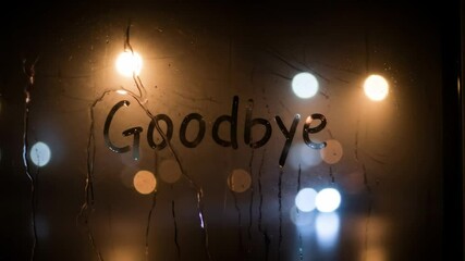 Goodbye Message on Foggy Window at Night - The word "Goodbye" is written on a rain-streaked window at night. Blurred city lights shine through the condensation, creating a moody atmosphere.
