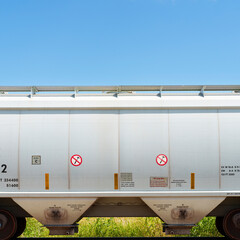 Hopper car with two No Hammer signs sits idle in a rail siding on a sunny Texas summer afternoon.