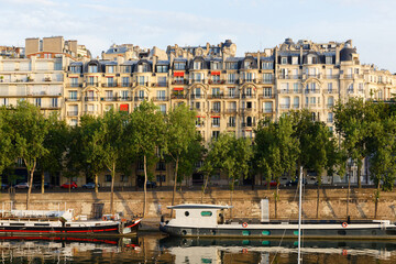 View of the traditional French houses and Seine River with barges in the foreground , Paris .