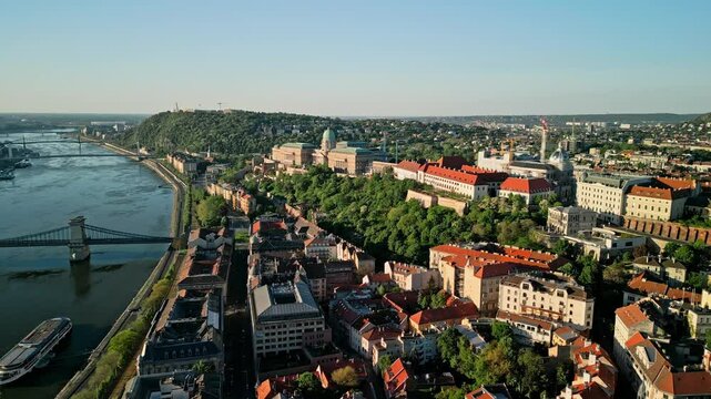 Aerial sunrise video from Fisherman's Bastion with sideward drone motion, keeping Buda Castle centered while revealing rooftops and historic architecture of Budapest&rsquo;s Castle District.  