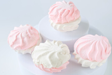 Two-tone marshmallows in pink and white elegantly arranged on light surfaces, exuding softness, sweetness, and delicacy. Photo