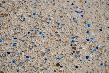 Close-up of a decorative beach pathway made of small natural pebbles embedded in concrete, with...