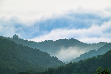 Naklejka premium Misty morning landscape with rolling clouds covering the mountains of Shulin District New Taipei City Taiwan, featuring the meteorological radar station on the peak.