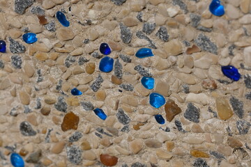Close-up of a decorative beach pathway made of small natural pebbles embedded in concrete, with...