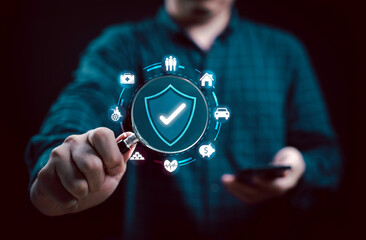 Businessman holds a magnifying glass with a shield icon for symbolizing security and protection in...