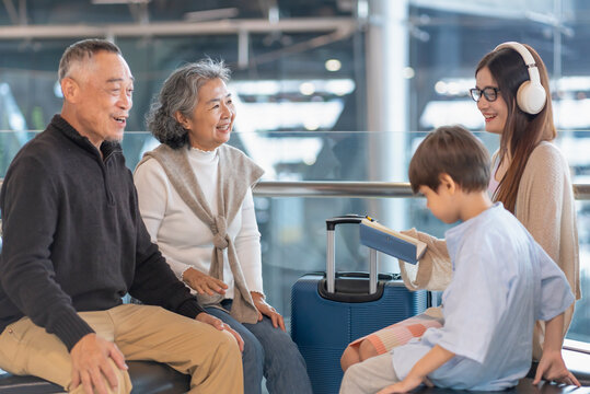 grandparent teasing with grandson,family having fun while waiting for boarding in airport terminal for summer vacation trip
