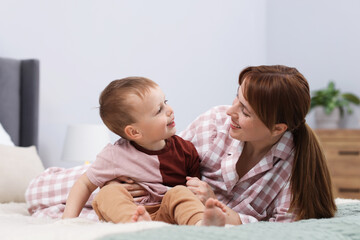 Happy mother spending time together with her son on bed at home
