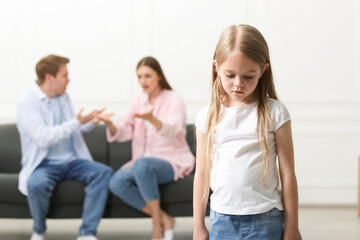 Fototapeta premium Upset little girl and her parents fighting at home, selective focus