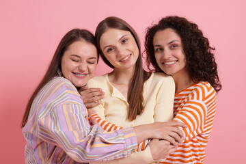 Friends hugging each other on pink background