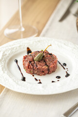 Beef tartare with caper and balsamic sauce on white plate
