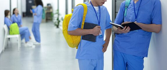 Medical student in uniforms with backpacks and notebooks at university, selective focus