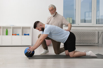 Obraz premium Doctor and patient exercising with medicine ball in clinic