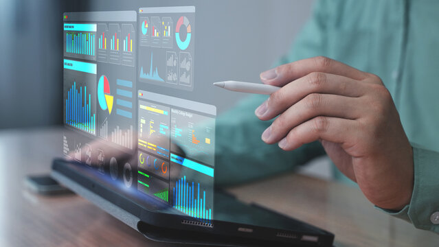 Professional using a stylus pen to control a digital dashboard displayed as a holographic interface from a laptop. The screen showcases data analysis, performance charts, and smart infographics.  - Powered by Adobe