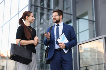 Happy coworkers discussing something near office building