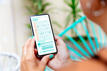 Woman looking the calendar app on mobile phone at the morning for planning the day. Digital...