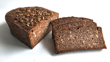 Whole grain bread loaf with seeds and three slices on white background
