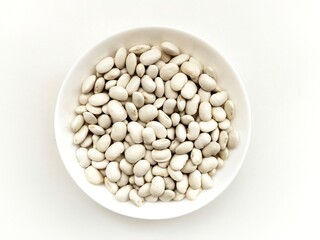 Top view of dried white beans in white bowl on white background
