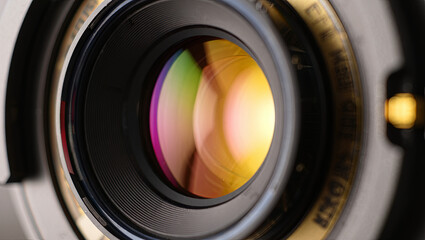 The close-up of a camera lens highlights its reflective surface, displaying bright colors and precise craftsmanship, ideal for capturing high-quality images during various photo shoots
