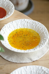 Clear chicken soup with herbs in white bowl on wooden table