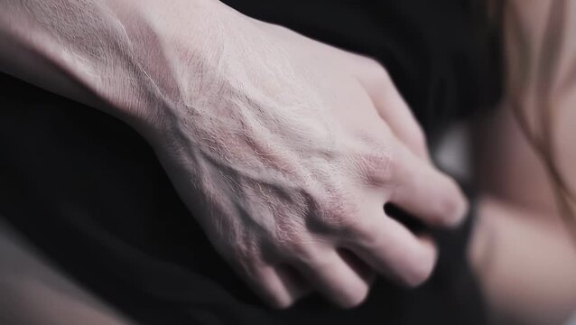 A striking closeup captures a pale, veiny hand and forearm in slow motion. A white substance on the skin slowly fades, making the dark, branching veins stand out in sharp detail.