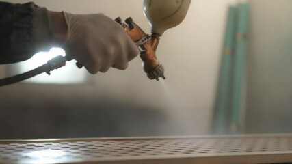 Painter applying varnish on wooden surface with spray gun