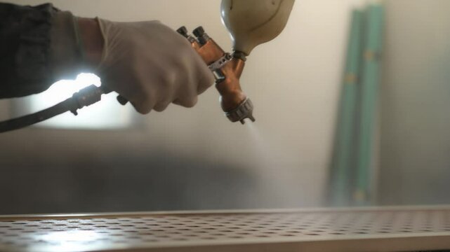 Painter applying varnish on wooden surface with spray gun