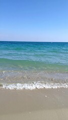 Clear, sunny beach scene; ocean waves gently reach the shore