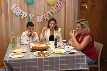Celebrating a boy's birthday, the family sits at the table, drinks and treats. Birthday...