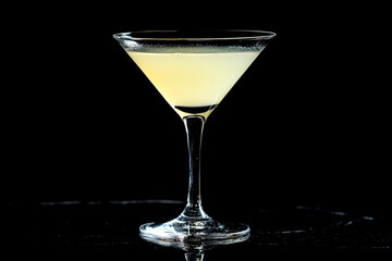 A beautifully crafted cocktail is displayed in a tall glass, showcasing its delicate color against a solid black background, emphasizing its allure