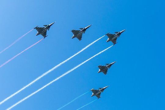 Five gray fighter jets with red white green colors in the blue sky