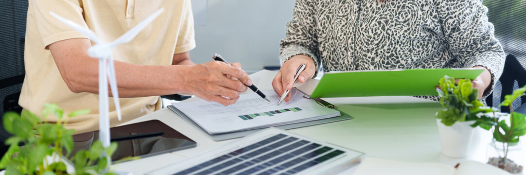 Business leaders reviewing ESG sustainability reports with renewable energy models for green investment planning - Powered by Adobe