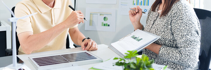 Asian adults discuss environmental social governance. Business experts review sustainability data for eco friendly development initiatives.